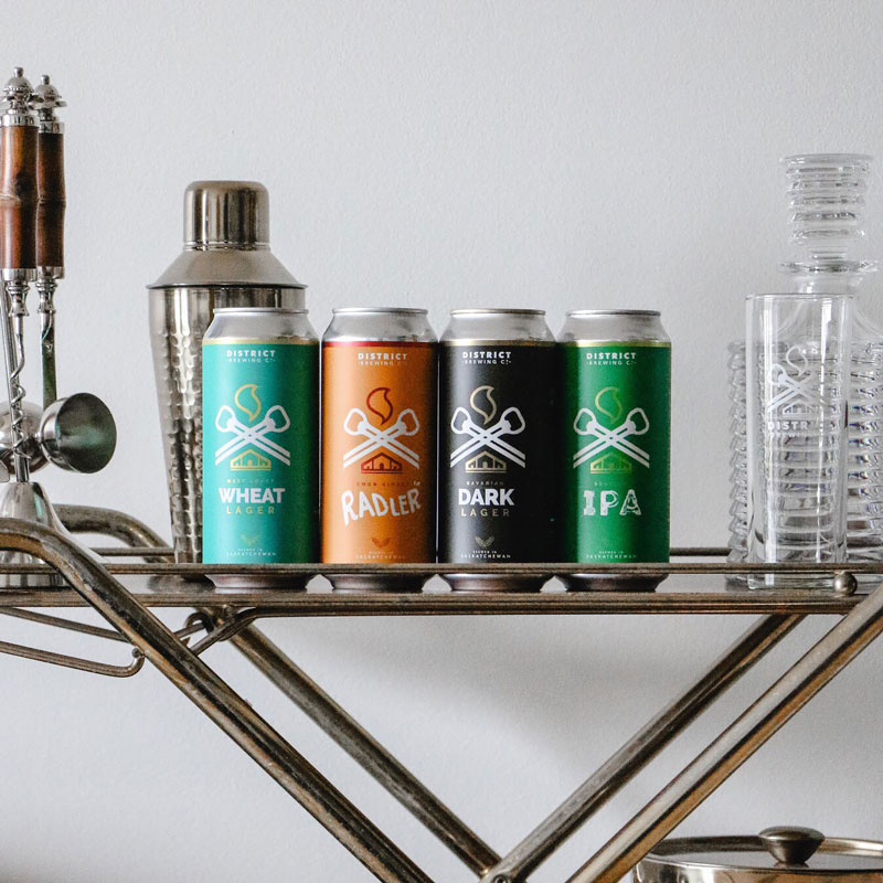 Four cans of beer lined up on a shelf.